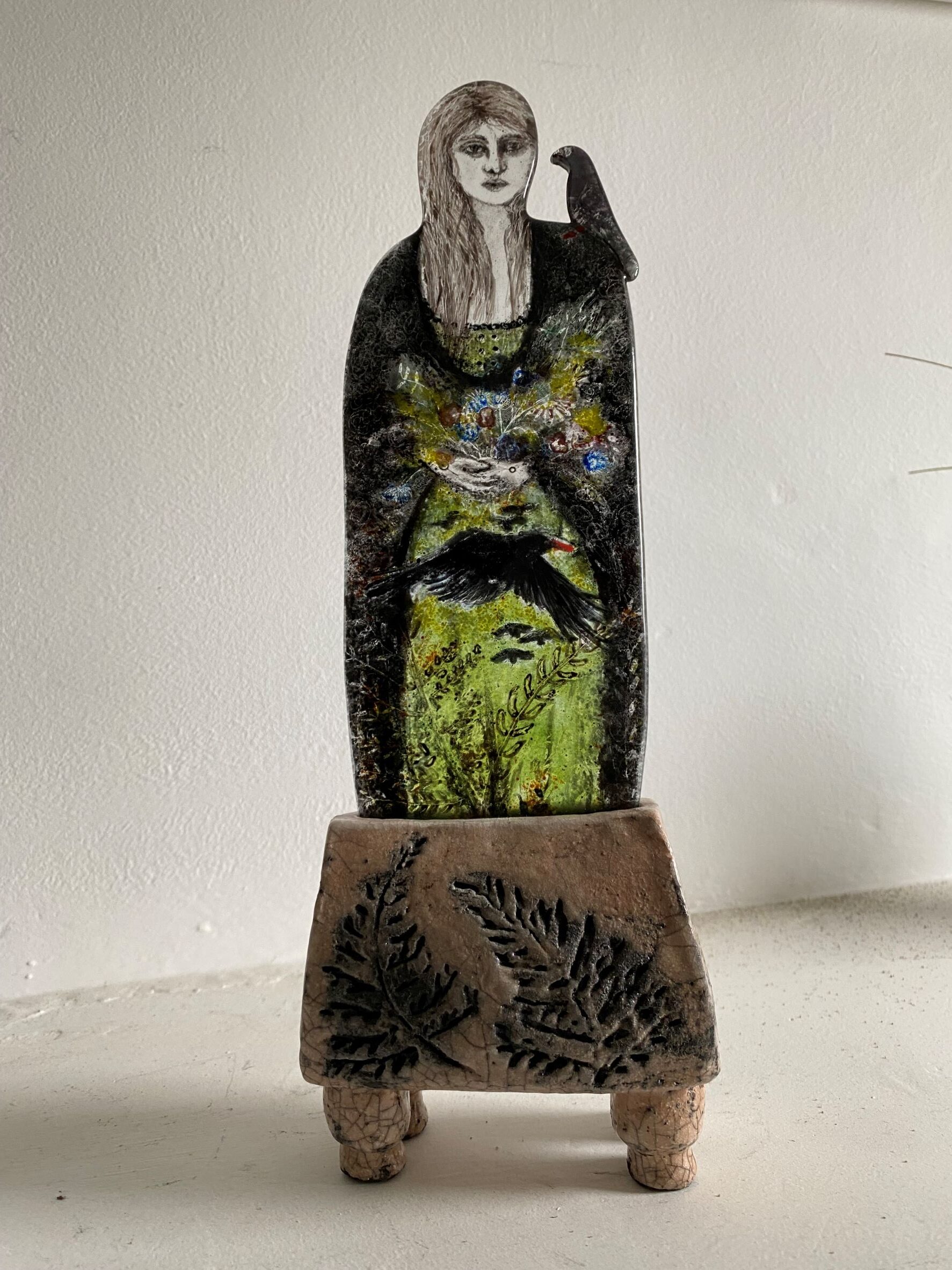 Woman and Chough Fused glasshand painted figure with Raku pottery base. 12" height